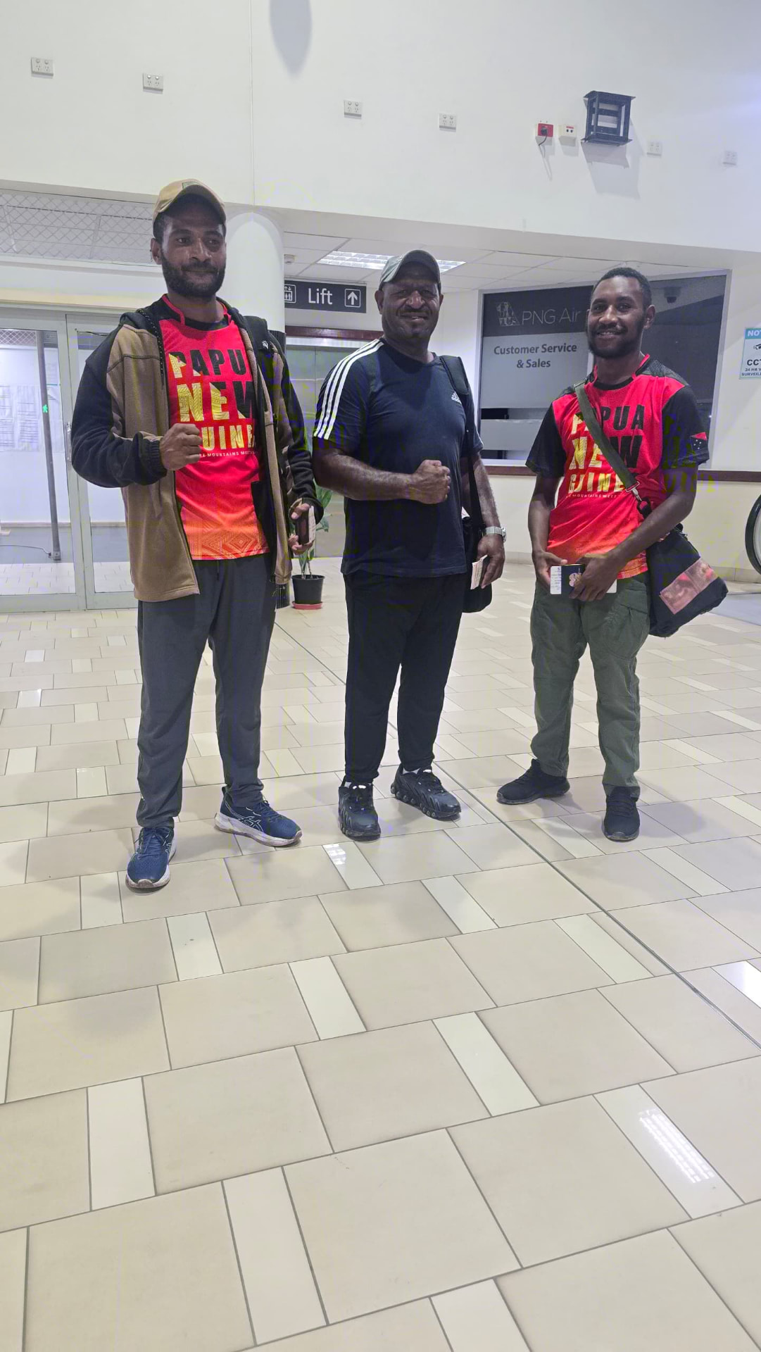 Three PNG team members in national jerseys at the PNG Air terminal