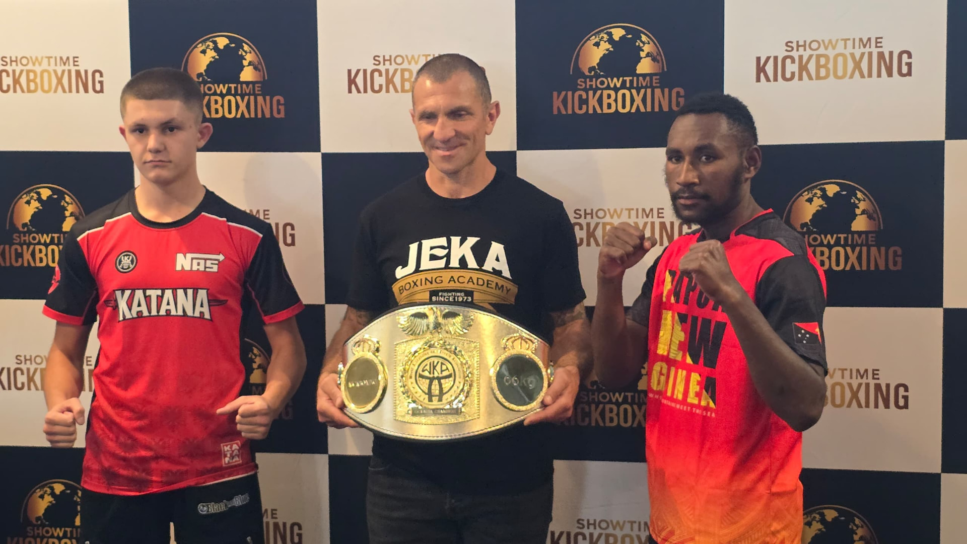 PNG fighter and opponent posing beside a WKA championship belt at a Showtime Kickboxing press wall