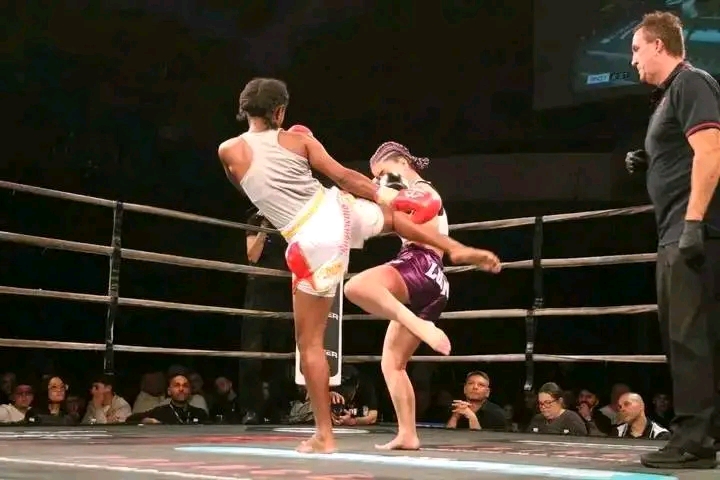PNG female Muay Thai fighter checking a high kick from her opponent in the ring