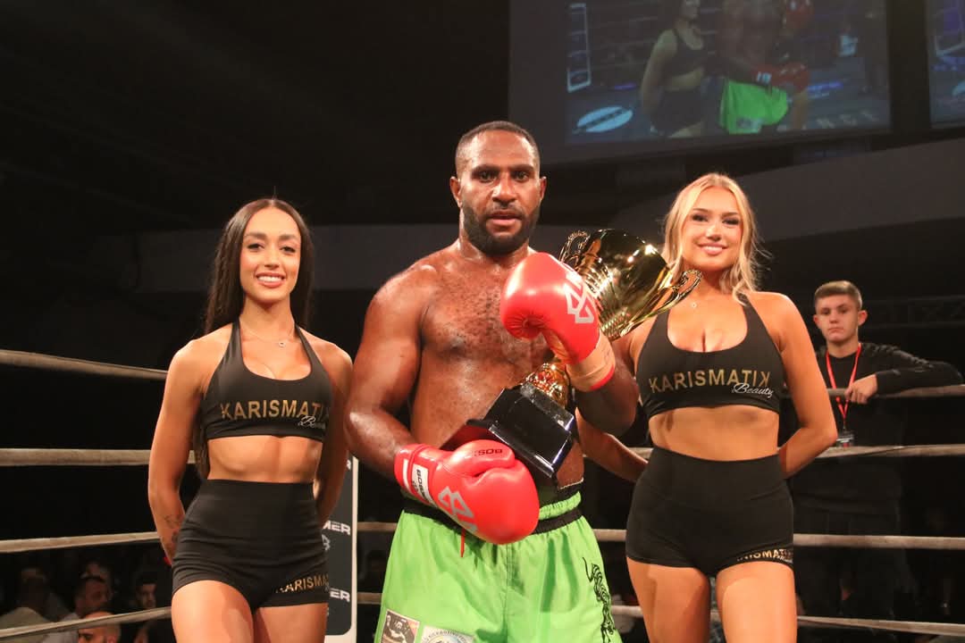Victorious PNG kickboxer in green shorts lifting the gold trophy